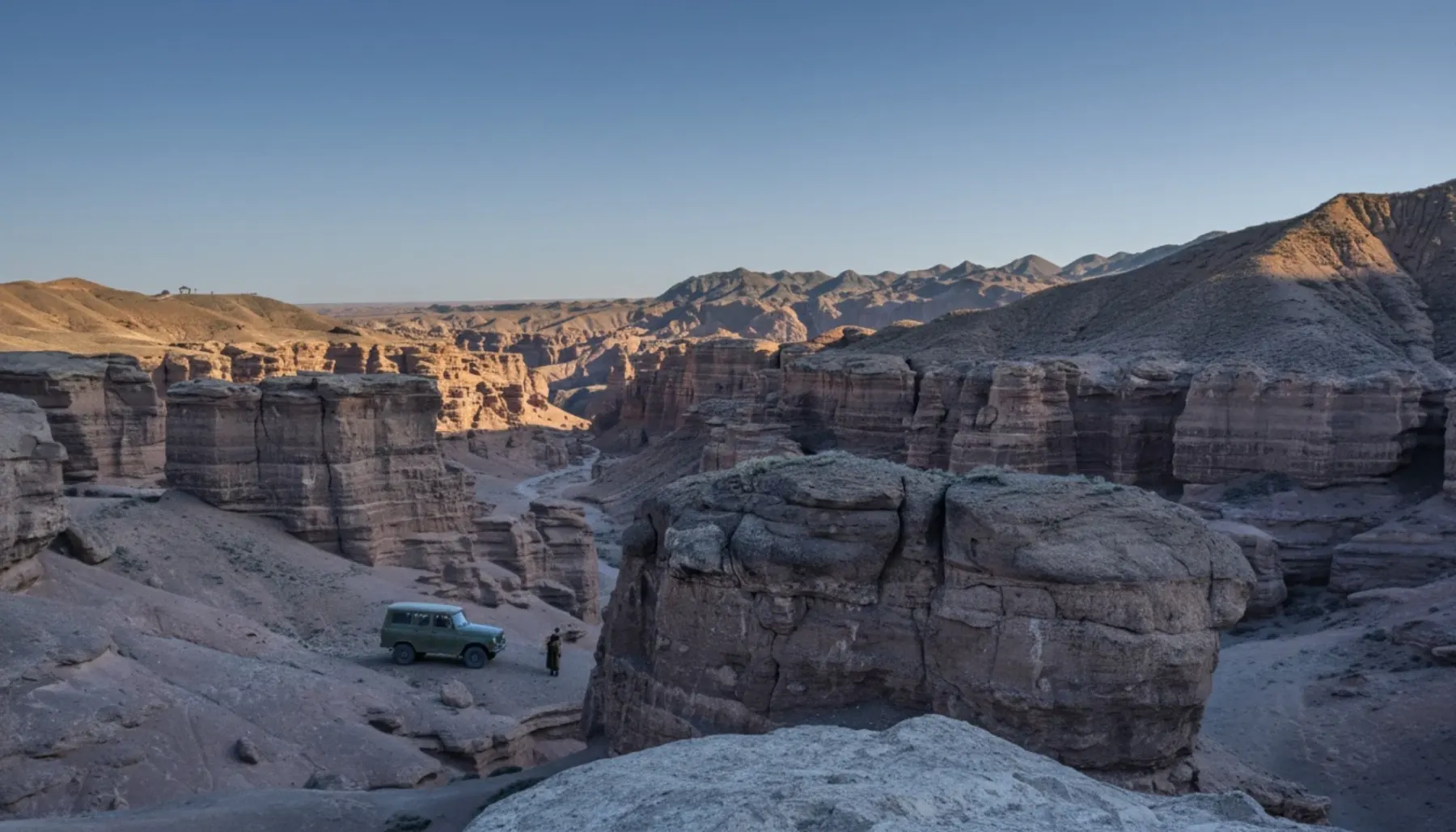 Vintage jeep at the edge of Charyn canyon, people on the rim